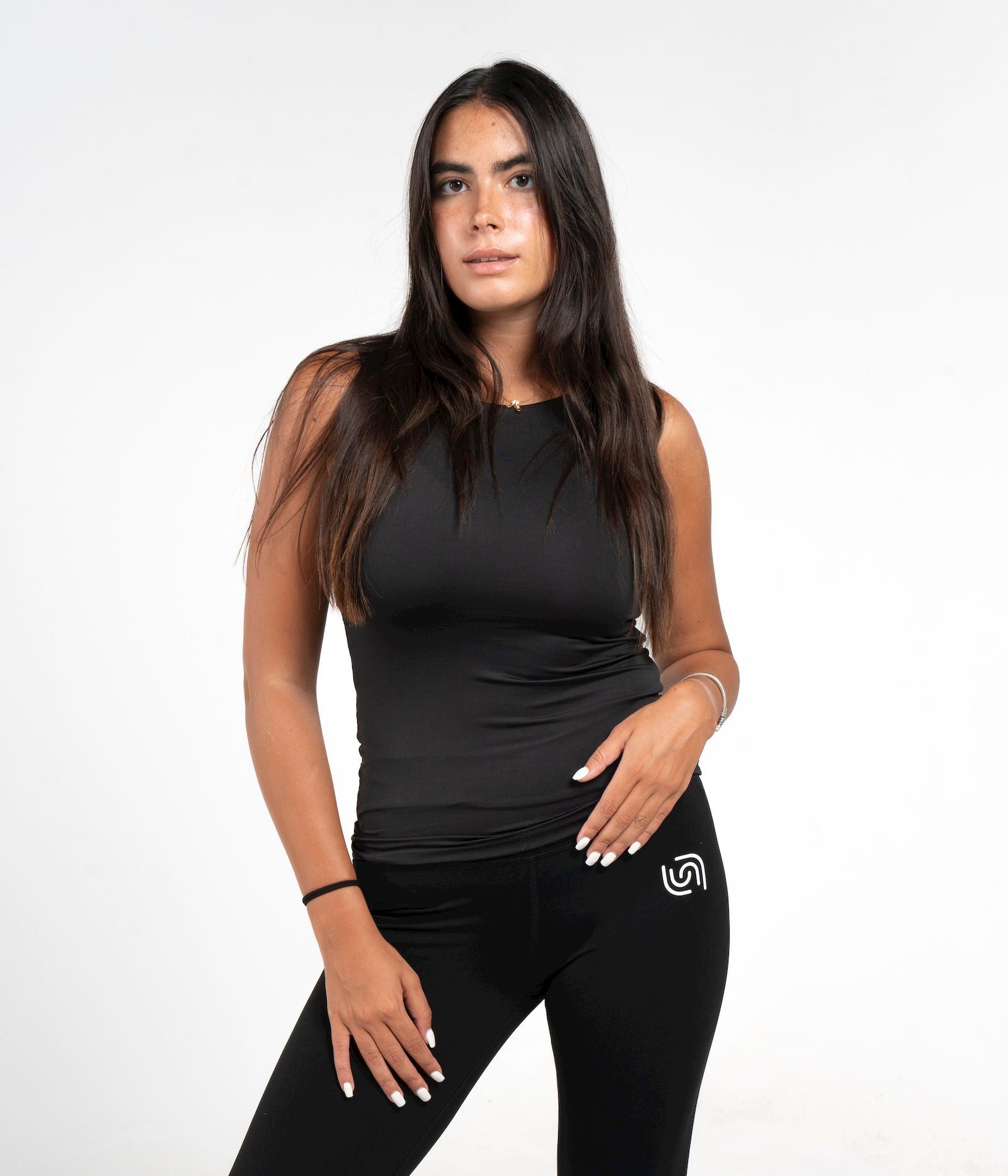 Woman wearing a black sleeveless top and leggings with a logo on a white background